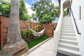 Unwind in your private backyard oasis. This tranquil space features a cozy hammock, perfect for lounging with a book under the shade of a tall palm tree.