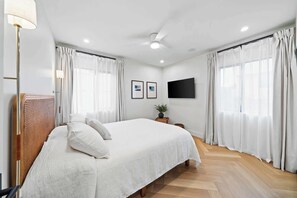Unwind in the primary bedroom. This spacious retreat features a queen-size bed, a smart TV, and ample natural light for a relaxing and peaceful stay.