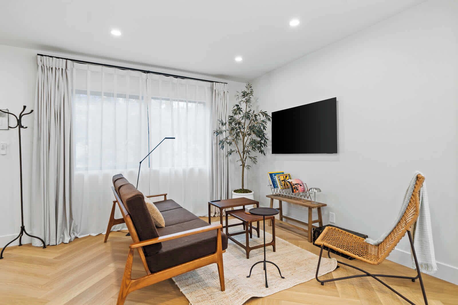 Wind down on the comfortable sofa and watch your favorite shows on the large flat-screen TV in this cozy, modern living room with bright, natural light.