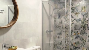 Une salle de bain moderne avec une douche à parois de verre, des toilettes blanches et un meuble-lavabo avec un miroir et un évier.
