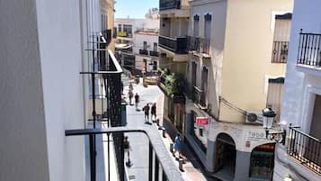 Una calle estrecha flanqueada por edificios, con una acera y un escaparate con señalización.