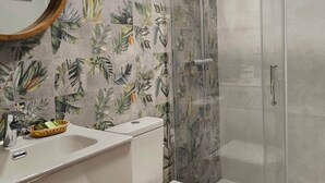 Une salle de bain avec douche, toilettes et lavabo.