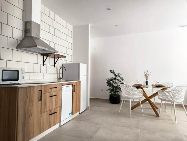 A modern kitchen with white tiles, wooden cabinets, a built-in microwave, and a dishwasher.