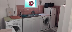 A compact laundry room with a washing machine, dryer, and a small sink with a faucet.
