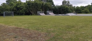 Ein grasbewachsenes Feld mit einem Fußballtor und einem Skatepark.