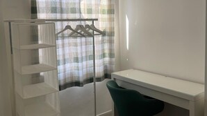 A room with a white desk, a green chair, a white shelving unit, and a clothing rack with hangers. - Manchester Dream House by Cambrian Street (Manchester)