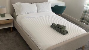 A neatly made bed with white bedding and folded towels on the footboard. - Manchester Dream House by Cambrian Street (Manchester)