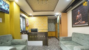 A reception area with a reception desk, two green sofas, a patterned wall, and a Buddha statue. - Hotel Liv By Yellow Bells (Hyderabad)