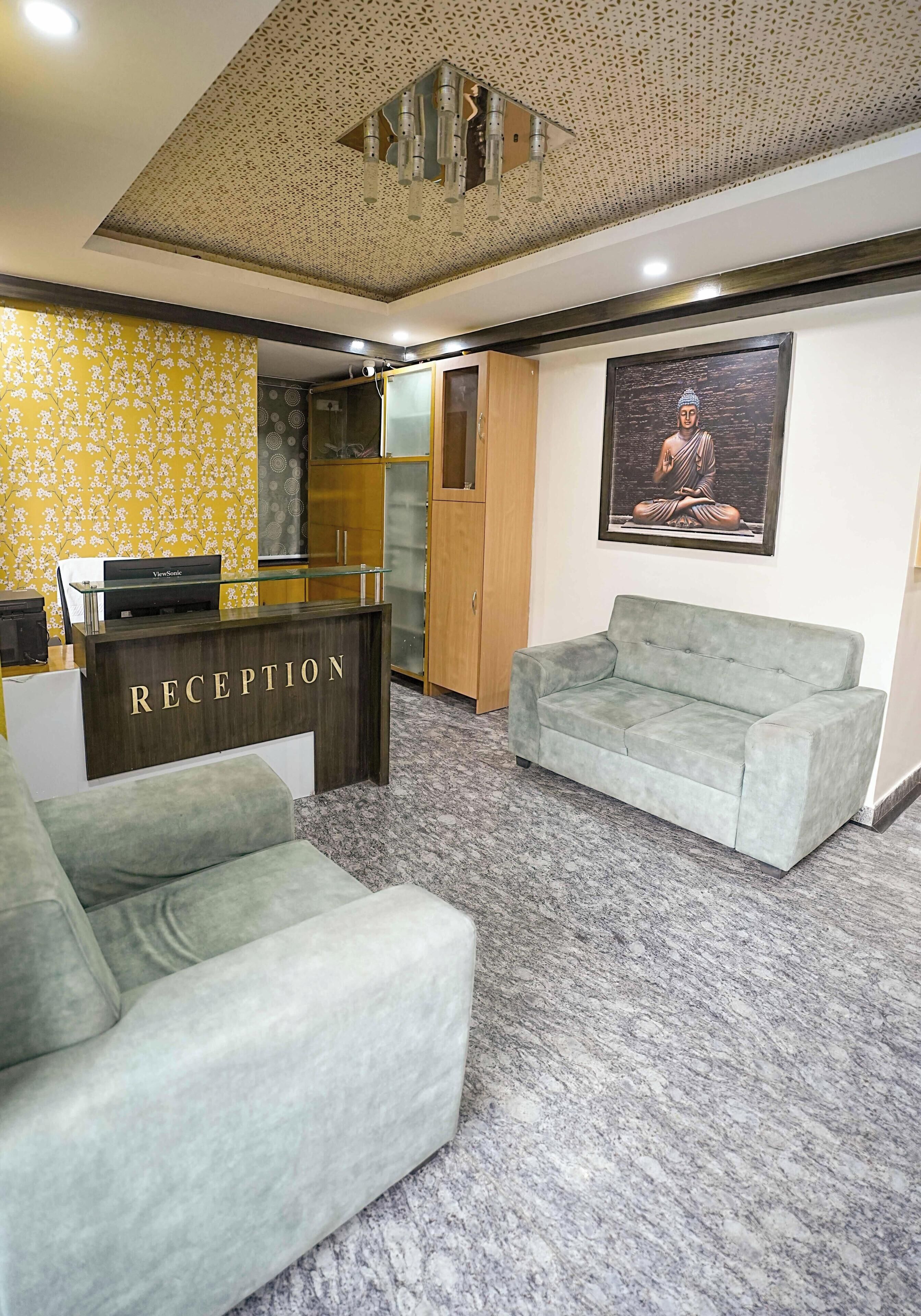 Een receptiegedeelte met een receptiebalie, een bank, een Boeddhabeeld en een gestreept plafond.