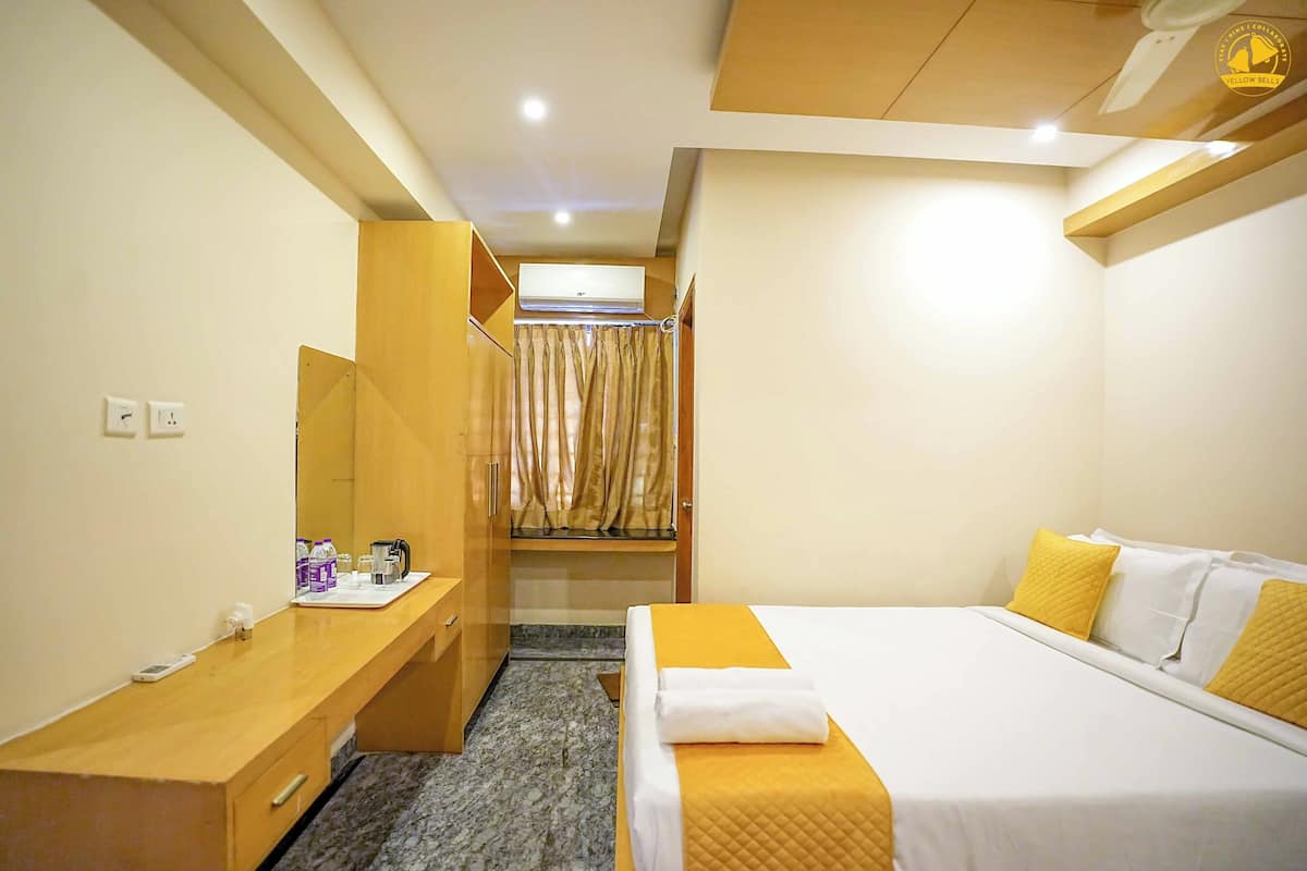 Een hotelkamer met een bed, bureau, garderobe en airconditioning.