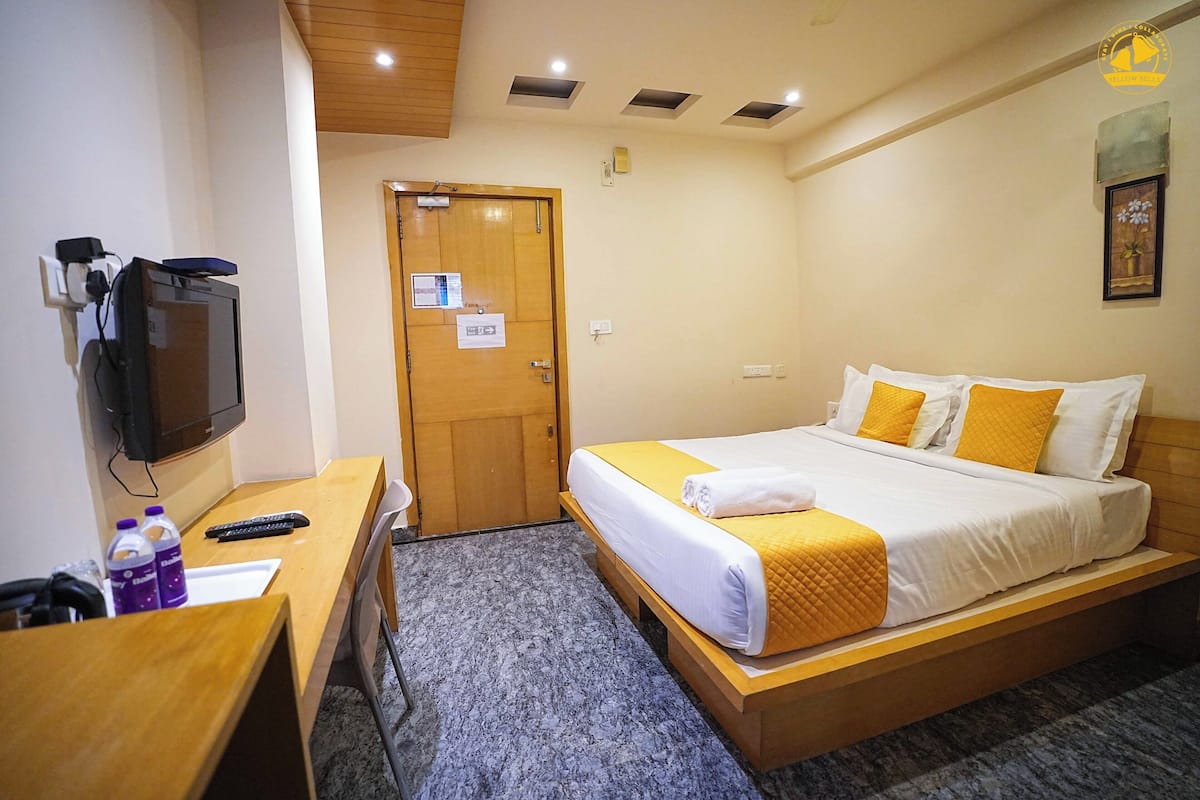 Een hotelkamer met een bed, een bureau, een televisie en een deur.