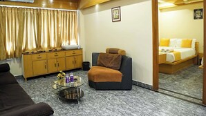 A hotel room with a marble floor, a sofa, a small table with a vase and bottles, a cabinet, a ceiling fan, and a bed with a yellow and white bedspread. - Hotel Liv By Yellow Bells (Hyderabad)
