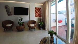 A modern living room with wicker chairs, a flat-screen TV, and potted plants. - BENCOMO SUNSET YOUR FAMILY APARTMENT NEXT TO LORO PARK (Puerto de la Cruz)