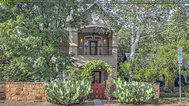 A house with a stone wall entrance, a front door, and a porch with a railing. - 3BR Retreat near South 1st St. | Walk to SoCo (Austin)