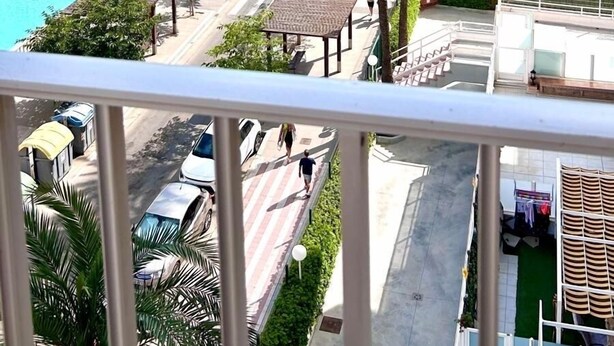 Un hotel con piscina, palme e vista sulla spiaggia.