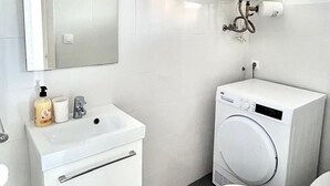 Un bagno moderno con lavandino, specchio, servizi igienici e scaldabagno bianchi.