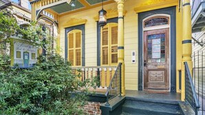 A yellow building with a wooden door and a balcony.