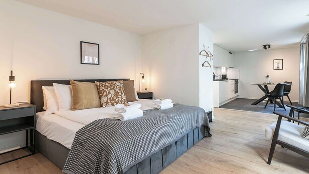 Een moderne hotelkamer met een groot bed, nachtkastjes, een bureau en een stoel.