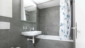 Een moderne badkamer met een wit wastafelmeubel, spiegel en bad.