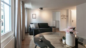 Una sala de estar moderna con una mesa de comedor de vidrio, un sofá negro y una mesita auxiliar.