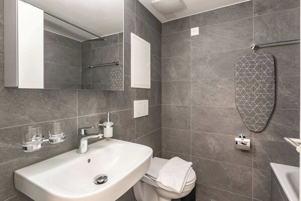 A modern bathroom with a white sink, a mirror, a towel rack, and a toilet.