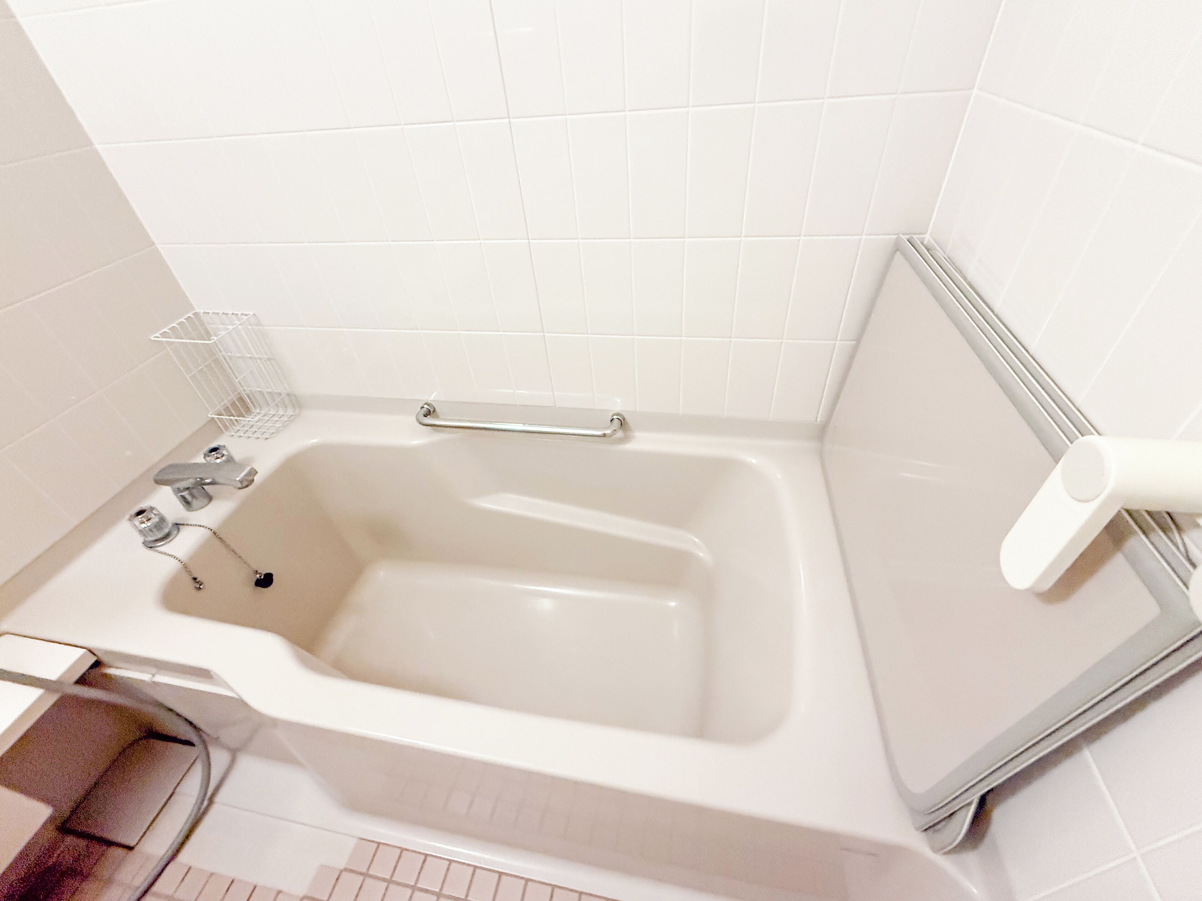 Egy modern fürőszoba, amelyben kád, kapaszkodó, törölközőtartó és WC-papírtartó található.
