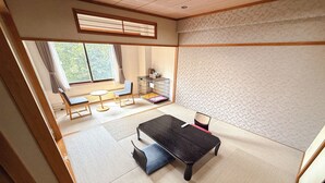 Une pièce de style japonais traditionnel, avec un sol recouvert de tatamis, une petite table basse avec des coussins et une porte coulissante donnant sur un balcon.