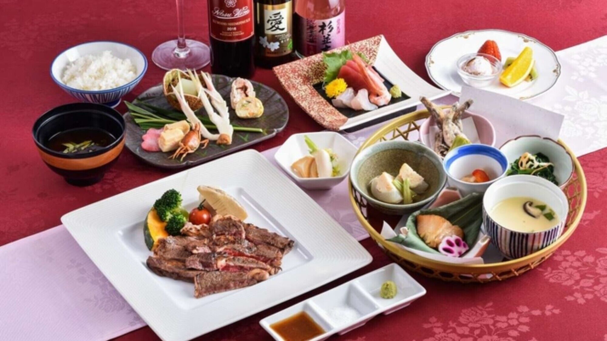 Ett urval av japanska rätter, inklusive sushi, sashimi och en skål soppa, upplagt på ett bord med en röd duk.