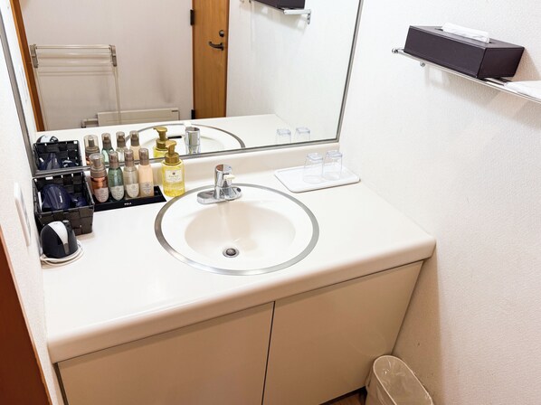 A bathroom with a white sink, mirror, and toiletries organized on a shelf. - Livemax Resort Nasukogen (Nasu)