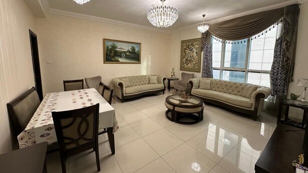 A spacious living room with a dining area, two sofas, a coffee table, and two chandeliers.