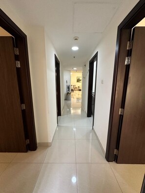 Un pasillo con piso de baldosas que conduce a una habitación con cama y ventana.
