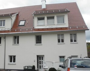 Un bâtiment à deux étages, doté d’un toit recouvert de tuiles rouges, de nombreuses fenêtres et d’une porte.