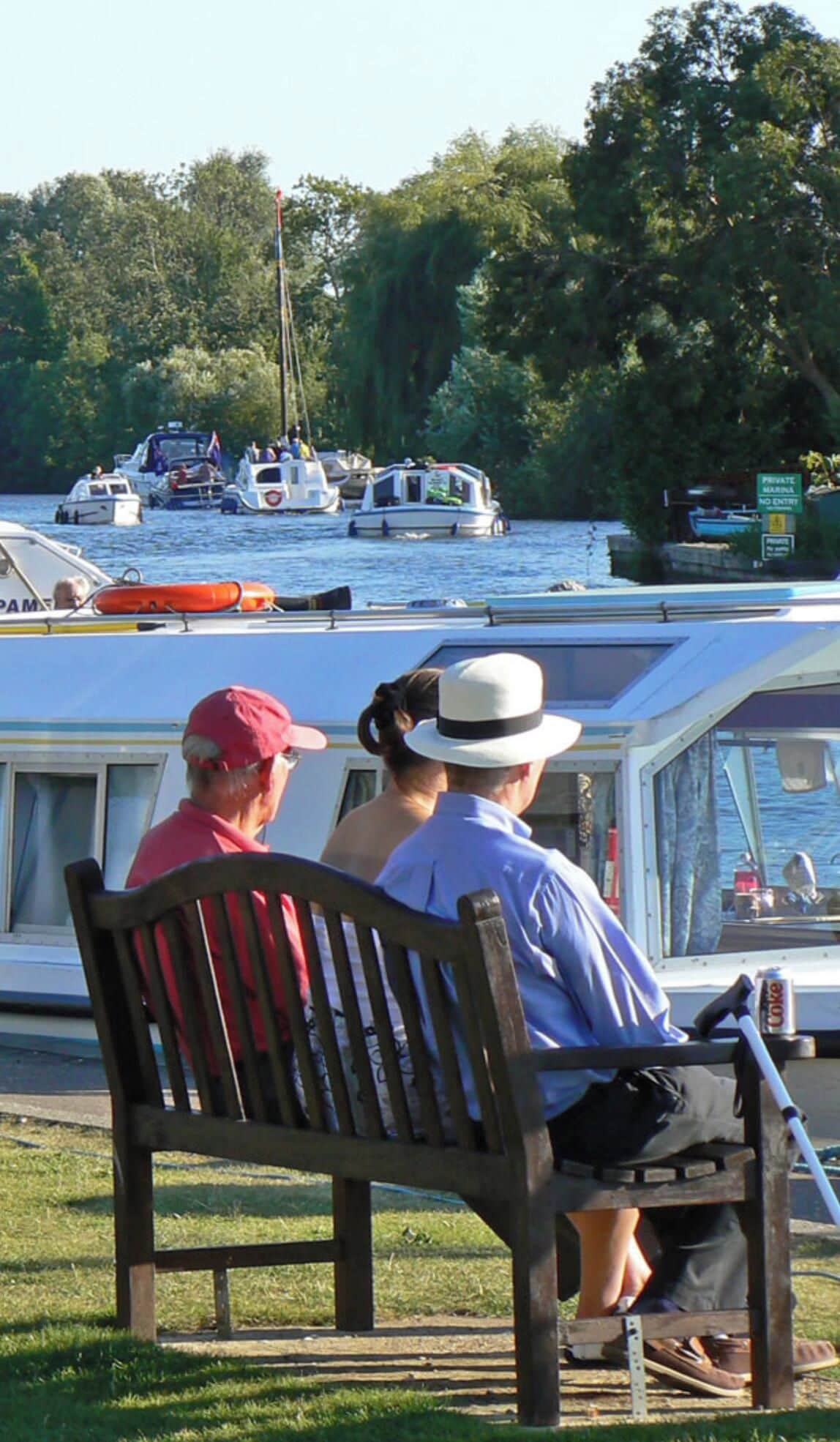 A couple sitting on a bench overlooking a marina with boats.