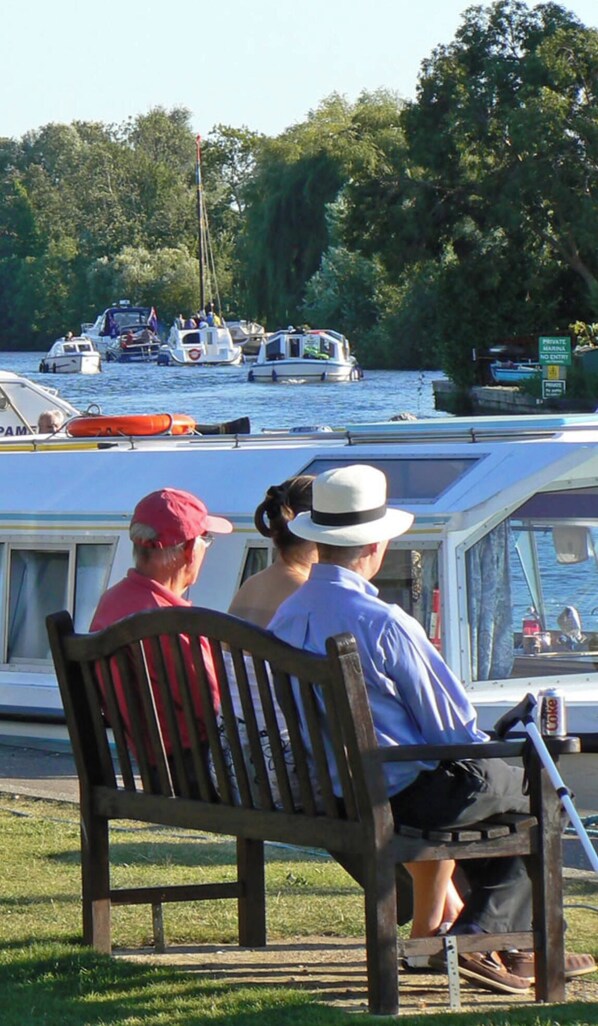 A bench with two people seated facing a body of water.