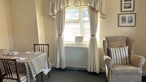 A dining area with a table set for two, a chair, and a radiator. - River breeze ground floor easy access with river view. Dog friendly. Sleeps 4  (Horning)
