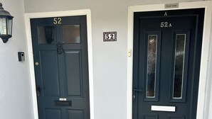 Two black doors with house numbers 52 and 52A, white trim, and a small sign indicating a river view. - River breeze ground floor easy access with river view. Dog friendly. Sleeps 4  (Horning)