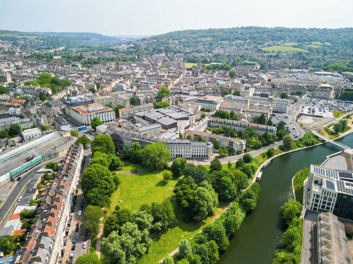 An aerial view of a city with a river, green spaces, and historic buildings.
