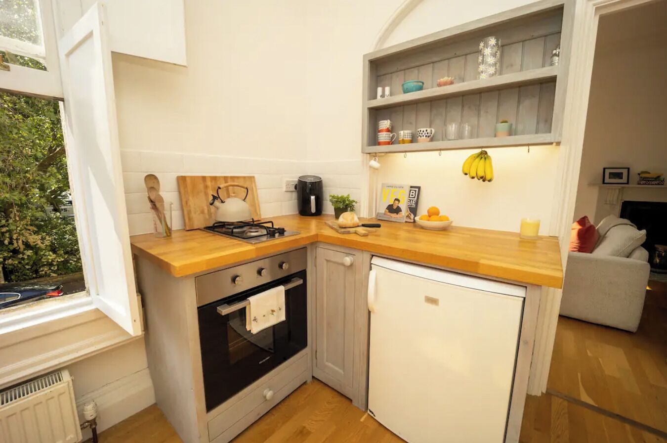 Una cocina compacta con estufa, horno y refrigerador, encimeras de madera y un ventanal pequeño.