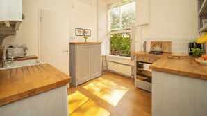 Une cuisine avec des plans de travail en bois, une cuisinière et une fenêtre donnant sur un paysage verdoyant.