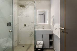 A modern bathroom with a glass shower enclosure, a marble-tiled wall, a vanity with a mirror, and a towel rack. - w Cozy 1BR in Polanco (Mexico City)
