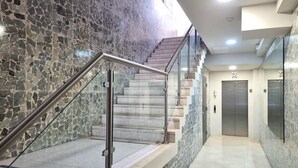 A modern interior with a stone-tiled wall, a metal staircase with glass railings, and a clean, tiled floor. - w Modern 2BR In La Cresta (Panama City)