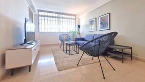 A spacious living room with a TV, a sofa, a chair, and a coffee table. - w Modern 2BR In La Cresta (Panama City)