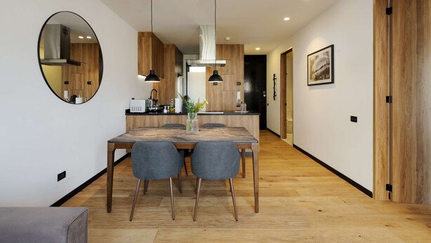 A modern kitchen with wooden cabinets, a dining table with chairs, pendant lights, and a large mirror on the wall. - w Fabulous 1BR With Elegant Balcony in Roma Nte (Mexico City)