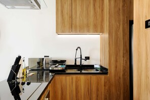A modern kitchen with wooden cabinets, a black countertop, and a stainless steel sink. - w Fabulous 1BR With Elegant Balcony in Roma Nte (Mexico City)