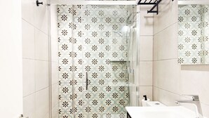 A modern bathroom with a glass-enclosed shower, a white sink, and a toilet.