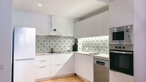 Una cucina moderna con mobili bianchi, un frigorifero in acciaio inox, un forno a microonde e un forno.