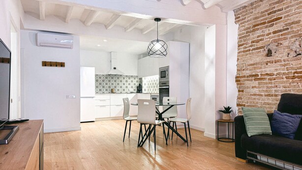Un soggiorno moderno con angolo pranzo, cucina e parete in mattoni.