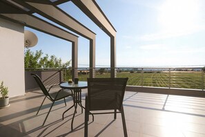 Ein Balkon mit Tisch und Stühlen, der einen Blick auf ein grünes Feld und die Ferne bietet.