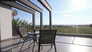 Ein Balkon mit Tisch und Stühlen, der Blick auf eine grüne Landschaft gewährt.
