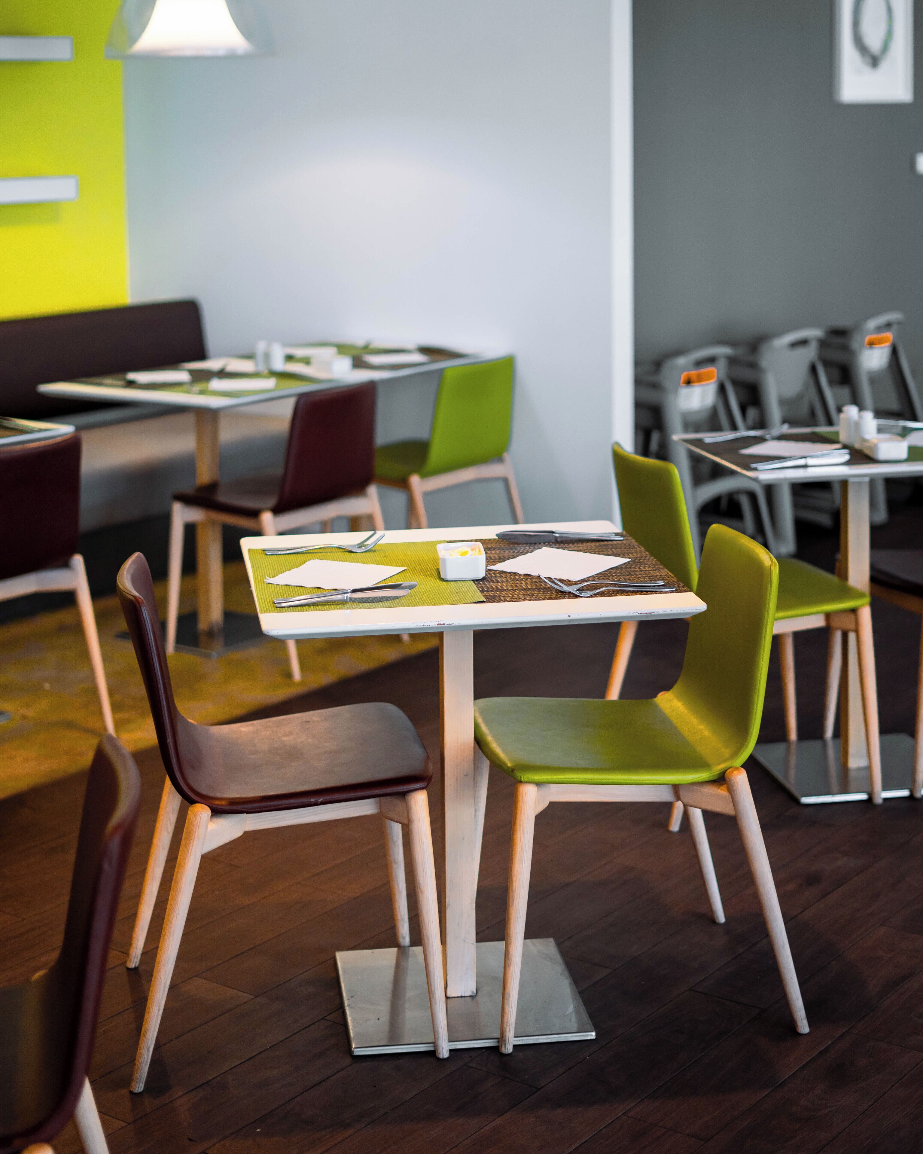 A modern dining area with wooden tables and green chairs.